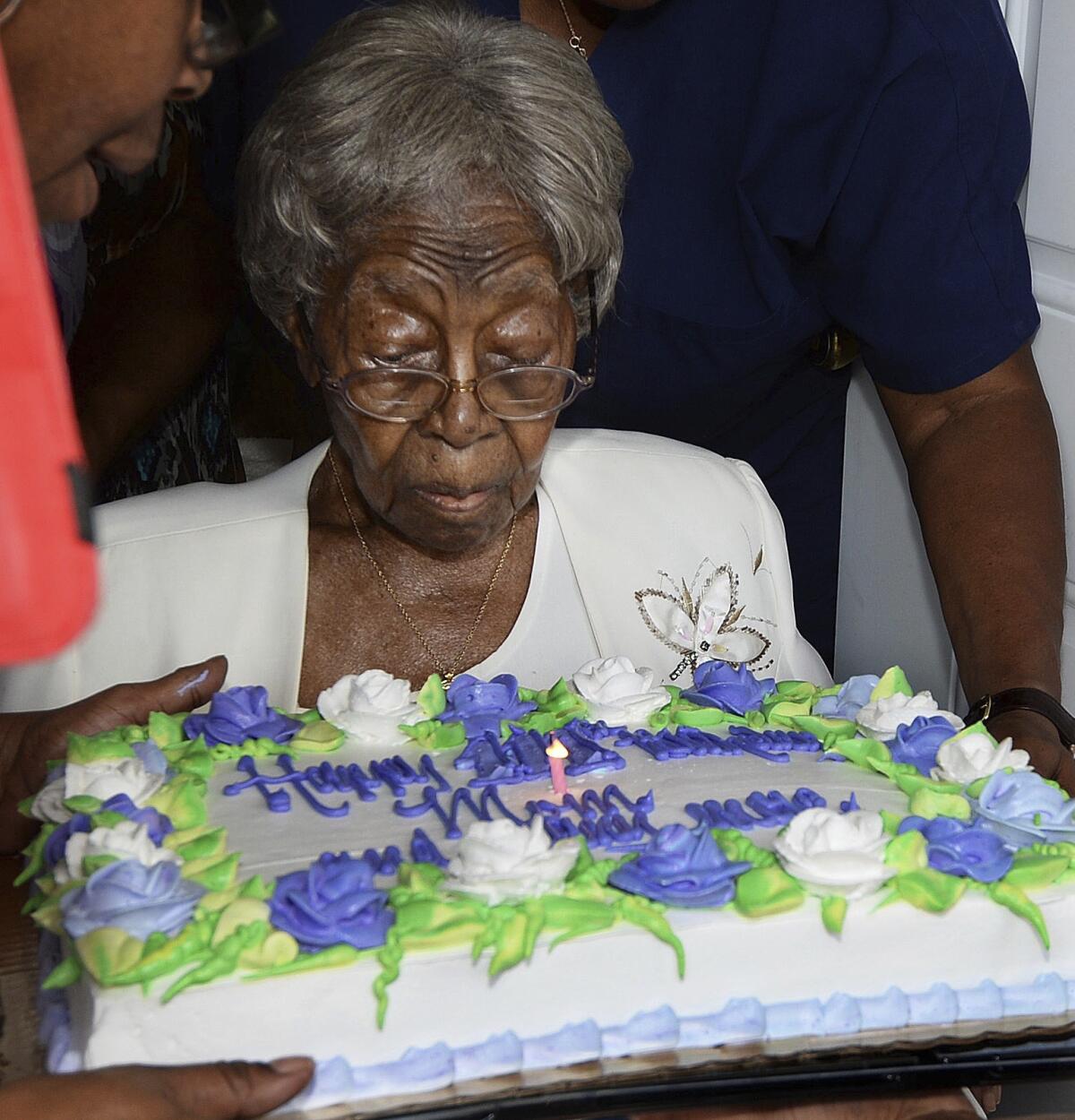 Hester "Granny" Ford at 111th birthday party blows out a candle on a cake decorated with flowers made of icing