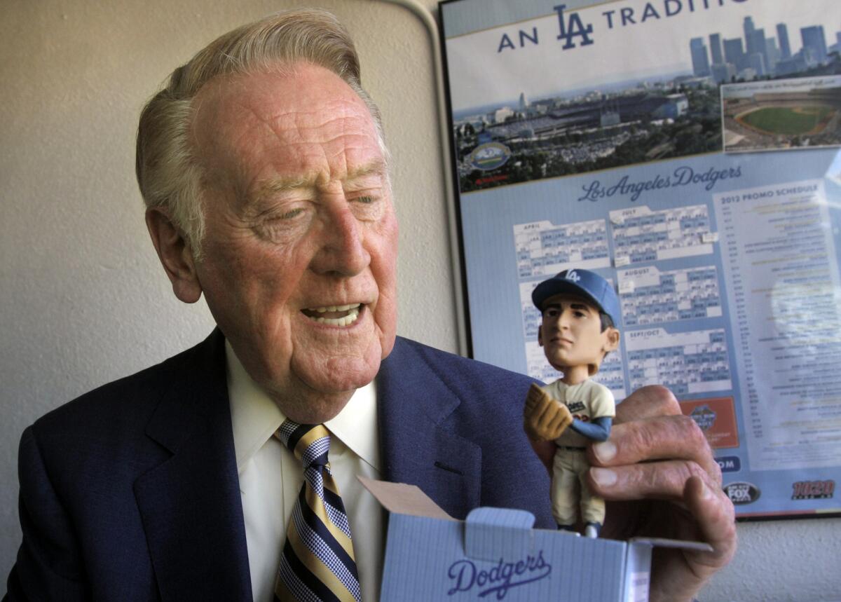 Dodgers broadcaster Vin Scully holds a Sandy Koufax bobblehead doll on August 7, 2012, the 47th anniversary of his call of the legendary pitcher's perfect game.
