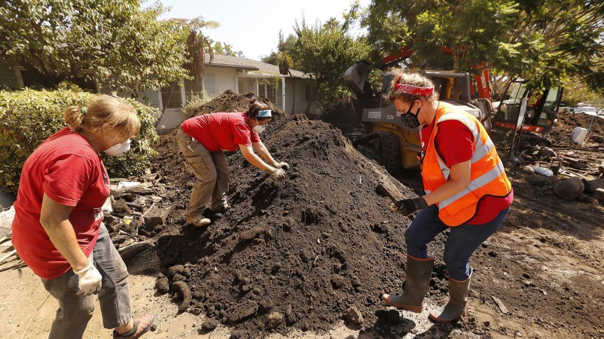 Jennifer Stafford, left, Ana Fagan and Denise Walden — volunteers with the Santa Barbara Bucket Brigade — sort through a dirt pile in the yard of a home damaged in the Montecito mudslides.