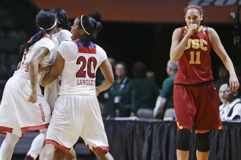 USC's Cassie Harberts, right, walks back to her team's bench as St. John's guard Keylantra Langley, center, celebrates with her teammates immediately following a game-clinching three-pointer by Briana Brown in the Trojans' 71-68 loss in the opening round of the women's NCAA tournament Saturday.