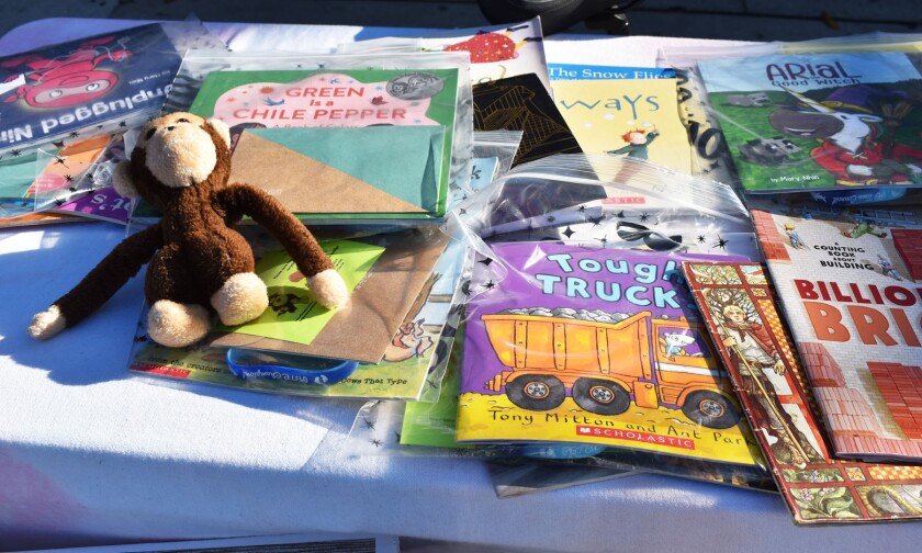 Stuffed monkey RJ with some of the children's books Tricia Goolsby bought by recycling cans and plastic bottles.