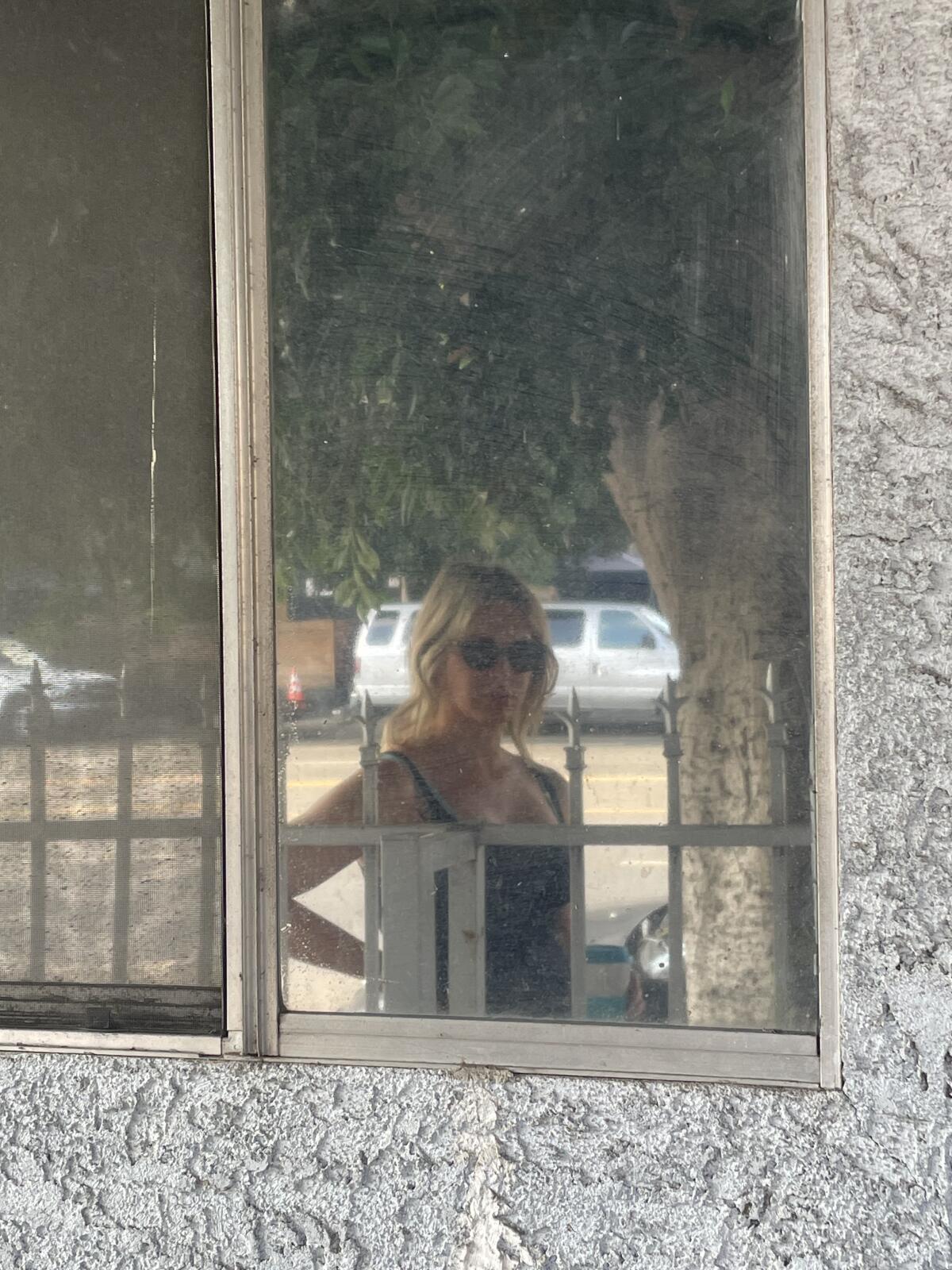 A woman reflected in a window while walking.