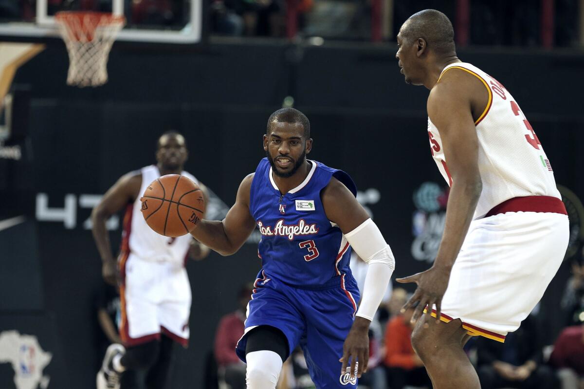 NBA Team World's captain Chris Paul dribbles and runs with the ball as Team Africa's Hakeem Olajuwon defends during and exhibition game Saturday in Johannesburg.