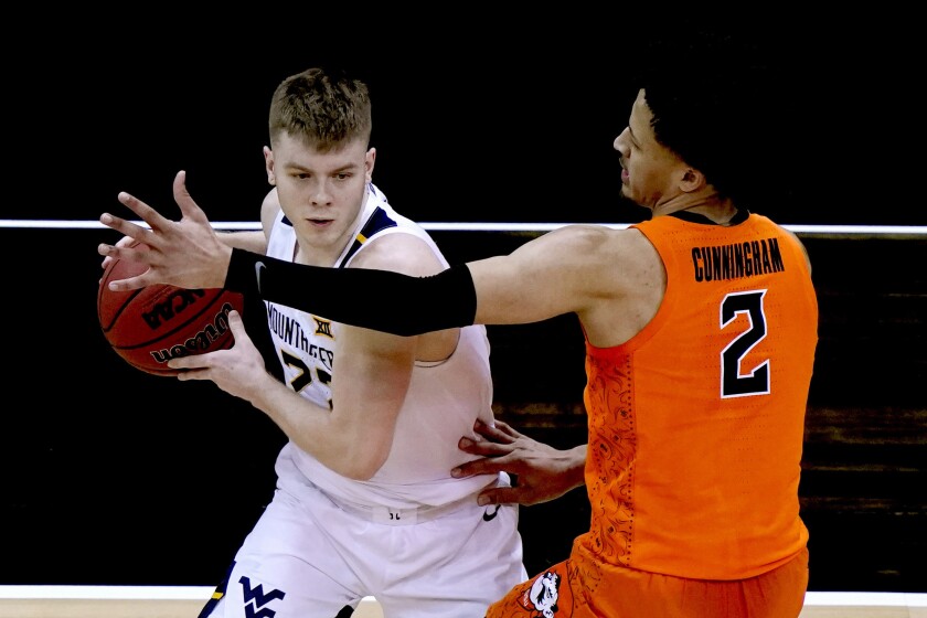 West Virginia's Sean McNeil is pressured by Oklahoma State's Cade Cunningham (2) during the first half of an NCAA college basketball game in the second round of the Big 12 Conference tournament in Kansas City, Mo., Thursday, March 11, 2021. (AP Photo/Charlie Riedel)