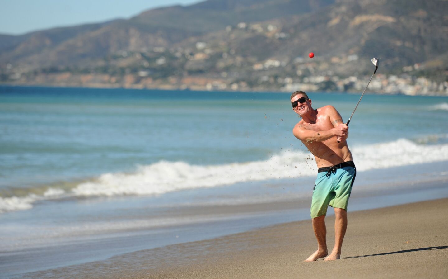 Dan Charcoal, who is vacationing in Southern California from Maui, golfs on Zuma Beach during a hot winter day Monday.