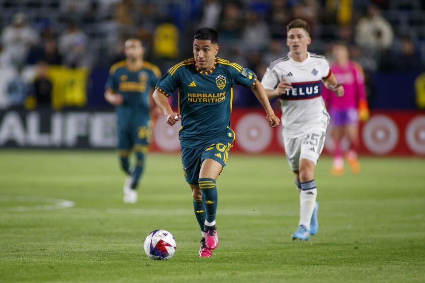 LA Galaxy midfielder Memo Rodríguez (20) controls the ball away from Vancouver Whitecaps midfielder Ryan Gauld (25) during the second half of an MLS soccer match in Carson, Calif., Saturday, March 18, 2023. (AP Photo/Ringo H.W. Chiu)