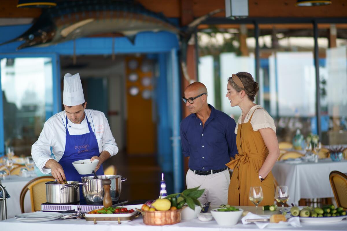 A couple stands in a restaurant watching a chef work.