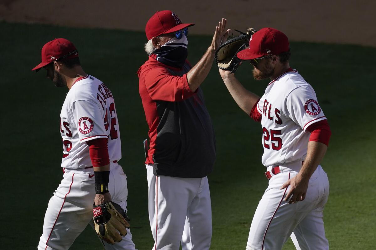 Angels manager Joe Maddon, center, high-fives right fielder Jared Walsh, right, after a win over the Texas Rangers.
