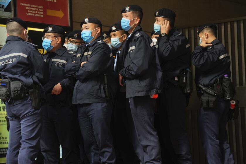 Police officers guard outside the building of Stand News' office in Hong Kong, Wednesday, Dec. 29, 2021. Hong Kong police arrest six members of online news outlet for sedition in continuing crackdown on dissent. Hong Kong police say they have arrested six current and former staff members of an online media company for conspiracy to publish a seditious publication. (AP Photo/Vincent Yu)