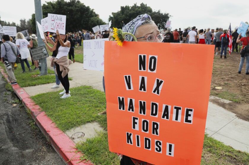 A person holds a sign that says "No vax mandate for kids" at a protest