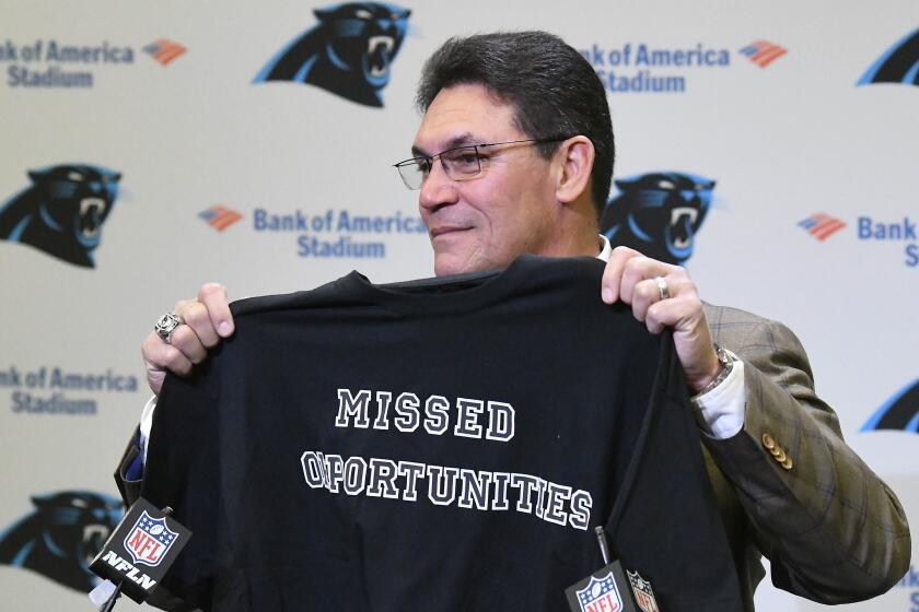 Former Carolina Panthers NFL football head coach Ron Rivera holds up a t-shirt at the end of a press conference at Bank of America Stadium in Charlotte, N.C., Wednesday, Dec. 4, 2019. Rivera was fired as coach on Tuesday. (David T. Foster III/The Charlotte Observer via AP)