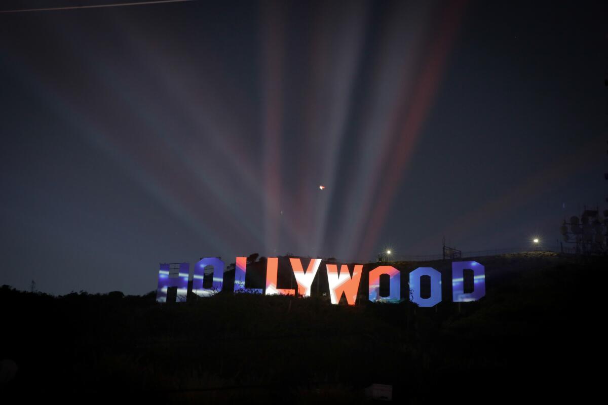 The Hollywood sign lit up at night with an American flag design