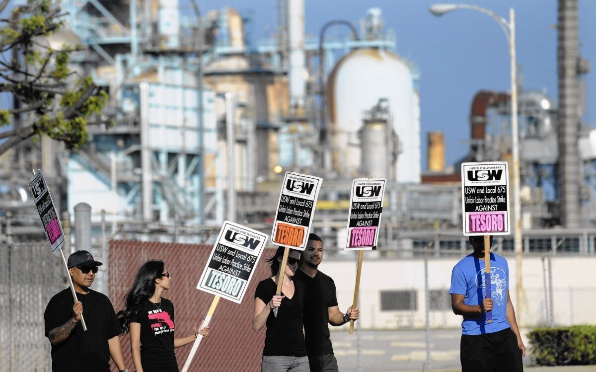 Striking worker walk a picket line outside the Tesoro Corp. oil refinery in Carson.