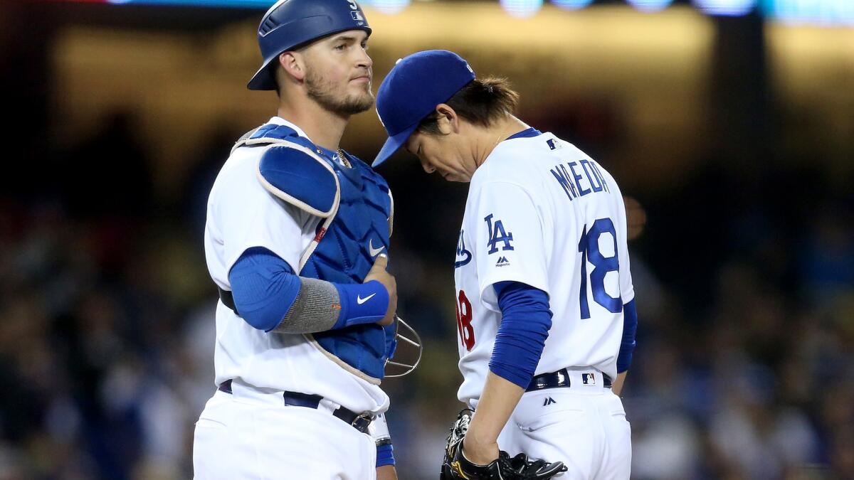 Dodgers starter Kenta Maeda is visited by catcher Yasmani Grandal moments before the pitcher is relieved in the seventh inning of a game against the Marlins on Thursday night.
