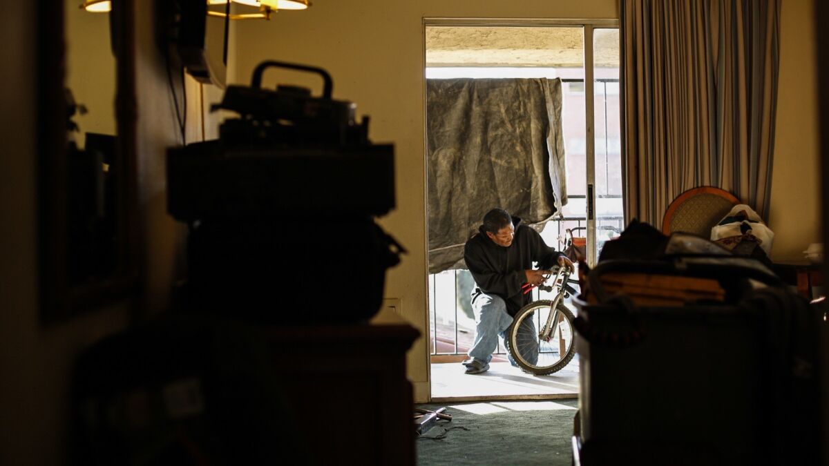 Donahue Farrow works on a bike on the balcony of his motel room. He's staying at the motel with a 30-day voucher from the Santa Ana riverbed cleanup but doesn't know what he'll do after his 30 days are up.
