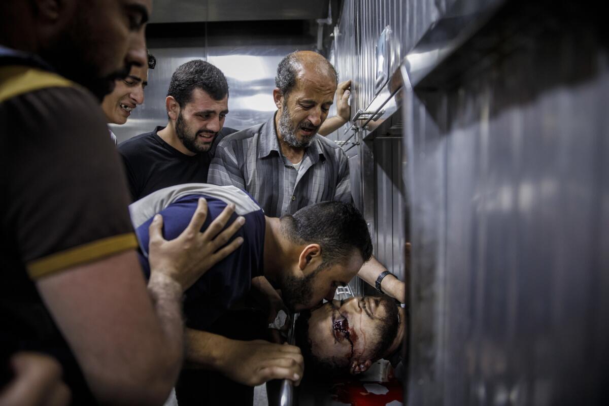 Ibraheem Mohammed Al-Tubassi, father, top, and other family members bid farewell to Yazan Ibraheem Mohammed Al-Tubassi, 23, at the Shifa Hospital morgue after he was shot by reportedly shot by Israeli forces.