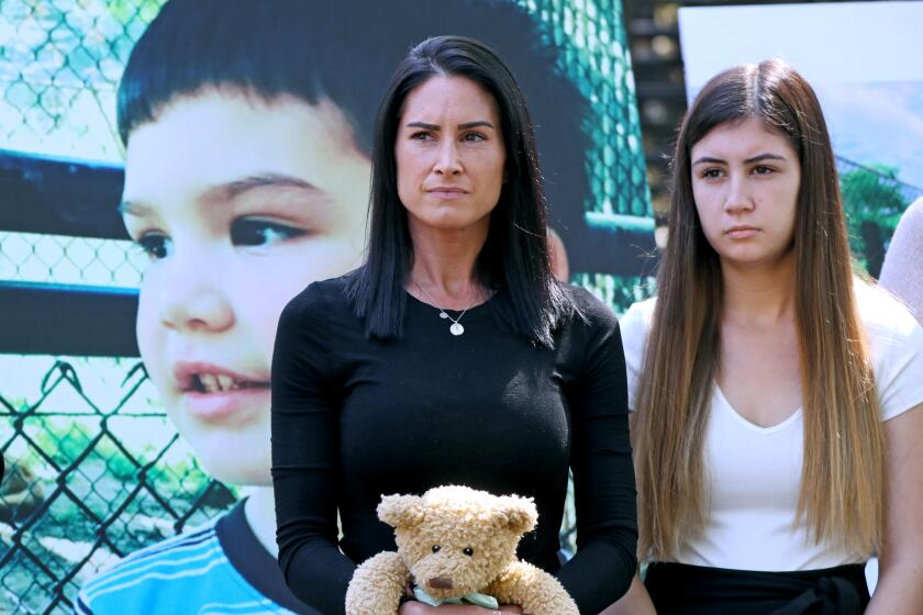 With a portrait of her 6-year-old Aiden Leos, Joanna Cloonan holds a teddy bear alongside her daughter, Alexis.
