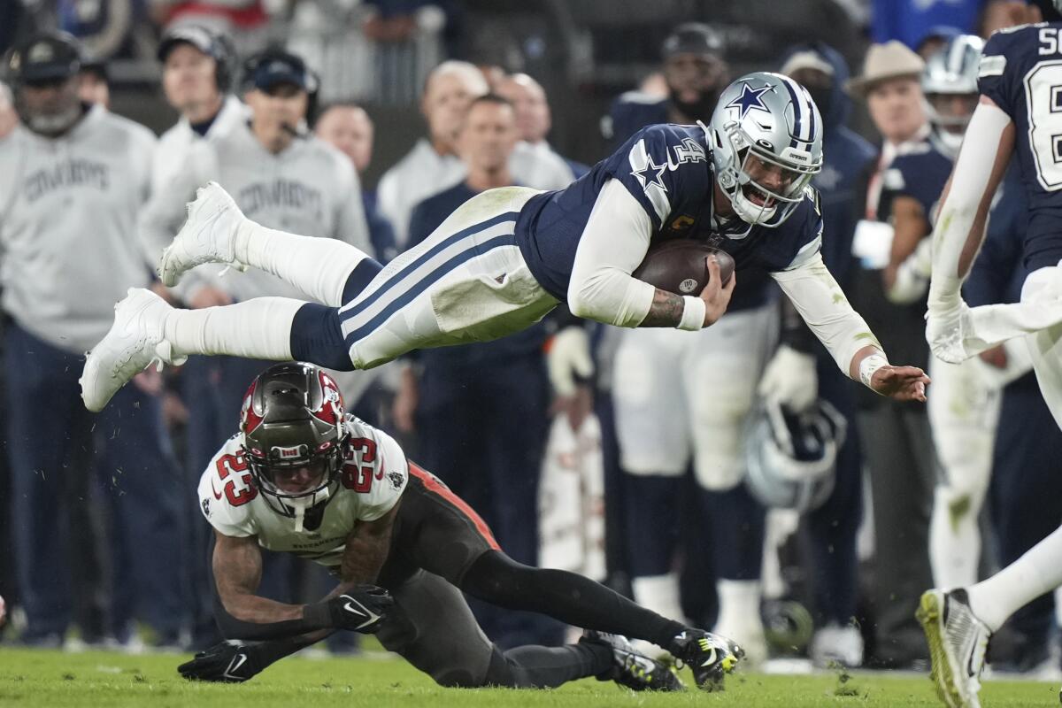 A player cradling a football dives above another player.