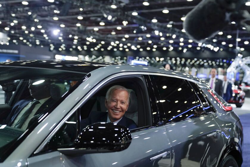 FILE - President Joe Biden drives a Cadillac Lyriq through the showroom during a tour at the Detroit Auto Show, Sept. 14, 2022, in Detroit. Biden persuaded Democrats in Congress to provide hundreds of billions of dollars to fight climate change. Now comes another formidable task: enticing Americans to buy millions of electric cars, heat pumps, solar panels and more efficient appliances. (AP Photo/Evan Vucci, File)