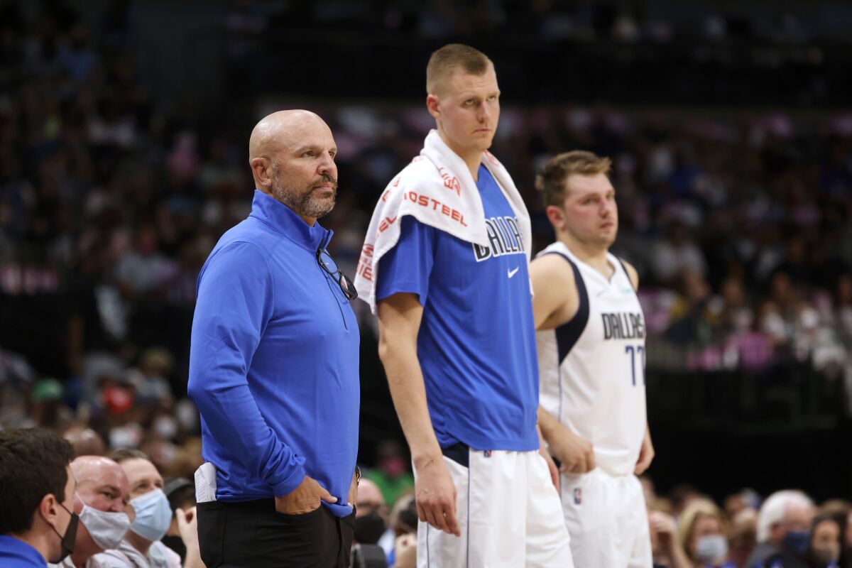 Dallas Mavericks coach Jason Kidd, left, forward Kristaps Porzingis, center, and guard Luka Doncic watch play in the first half of the team's preseason NBA basketball game against the Utah Jazz in Dallas, Wednesday, Oct. 6, 2021. (AP Photo/Michael Ainsworth)