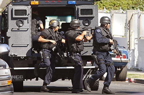 LAPD SWAT team members take positions near the corner of Malabar and Fickett streets in Boyle Heights, where an officer-involved shooting occurred. A detective sustained a gunshot wound to the leg as he tried to serve a narcotics warrant.