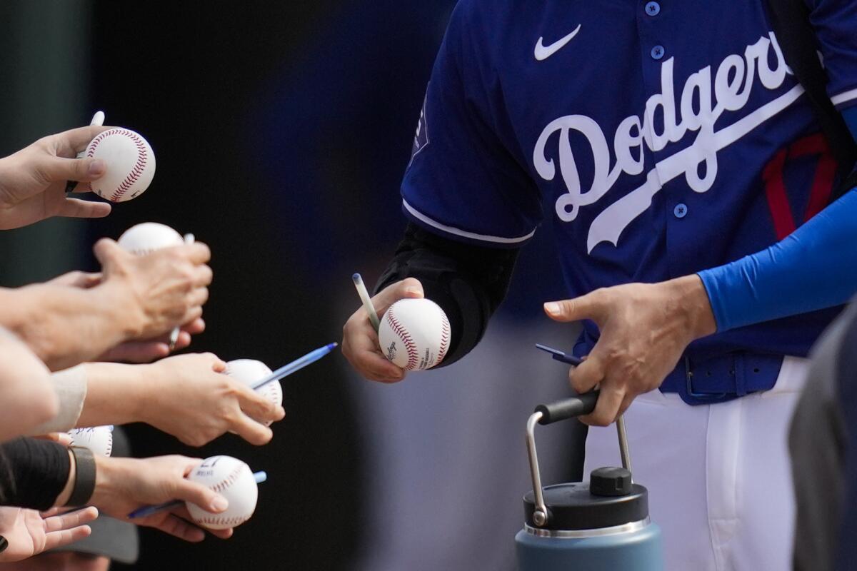 Dodgers designated hitter Shohei Ohtani signs autographs for fans before a game Tuesday against the Chicago White Sox.
