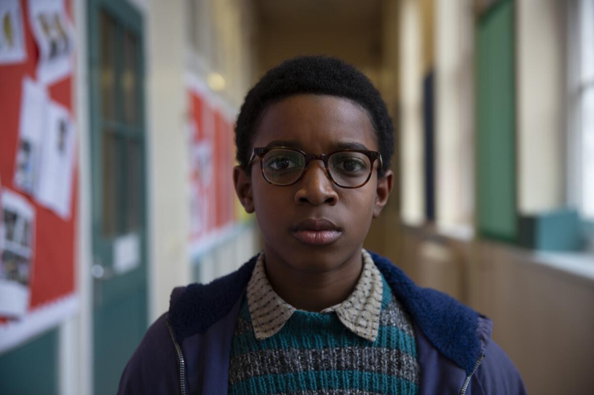 A bespectacled schoolboy in a green and gray knit sweater