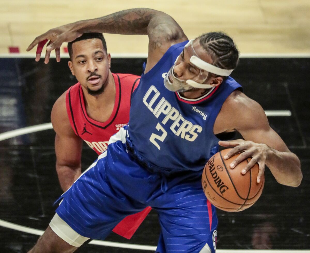 Clippers forward Kawhi Leonard tries to regain his balance while being covered by Portland guard CJ McCollum.