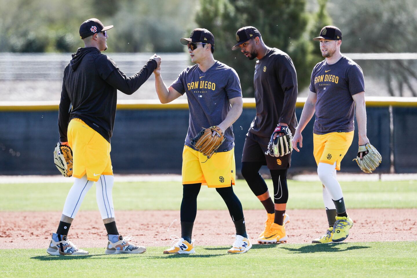 Padres third baseman Manny Machado high fives Ha-Seong Kim as they walk off the field with Xander Bogaerts and Jake Cronenworth during a spring training practice at Peoria Sports Complex on Thursday.