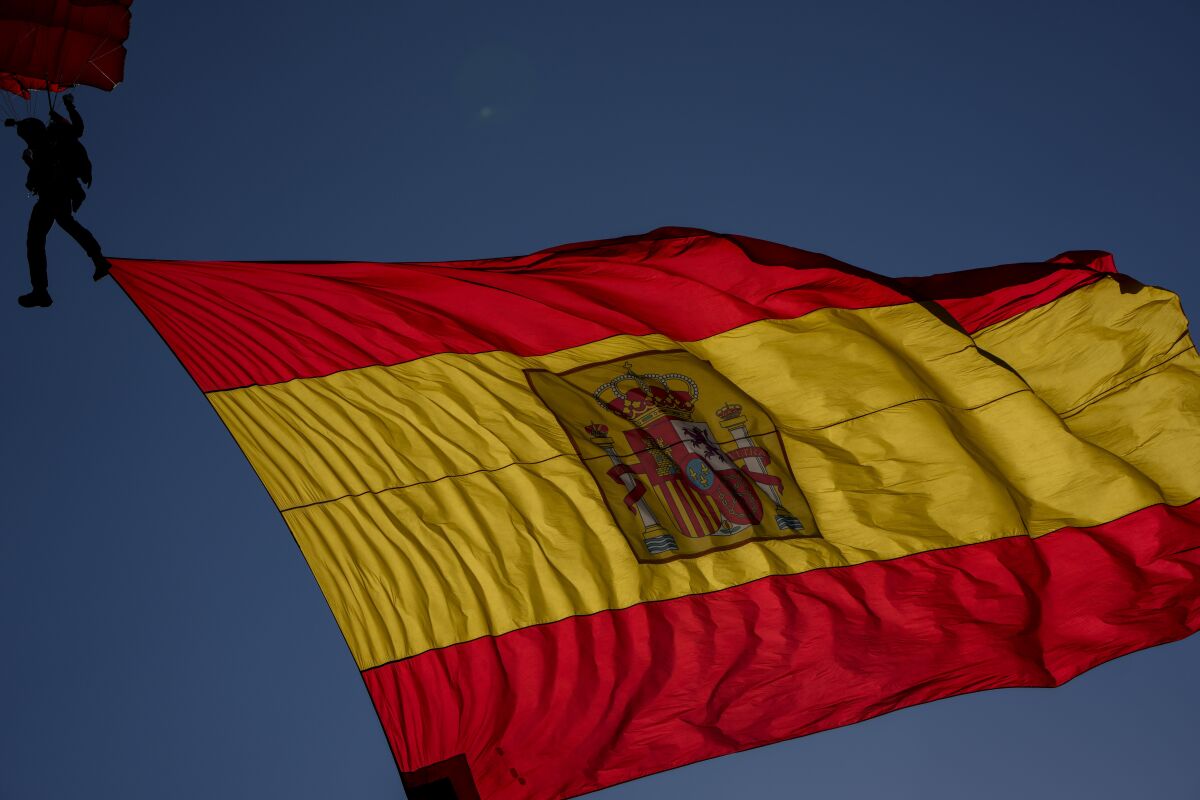 A paratrooper carries a Spanish flag during a military parade to celebrate a holiday known as 'Dia de la Hispanidad' or Hispanic Day in Madrid, Spain, Tuesday, Oct. 12, 2021. Spain commemorates Christopher Columbus' arrival in the New World and also Spain's armed forces day. (AP Photo/Manu Fernandez)