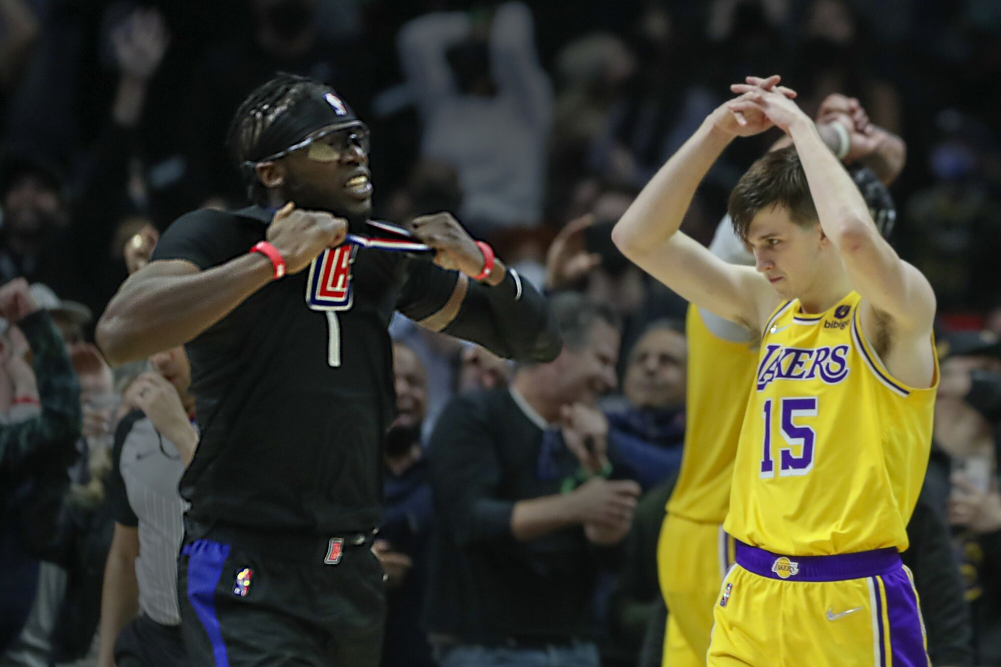 Clippers' Reggie Jackson celebrates winning basket by tugging on jersey while Lakers' Austin Reaves throws his arms overhead.