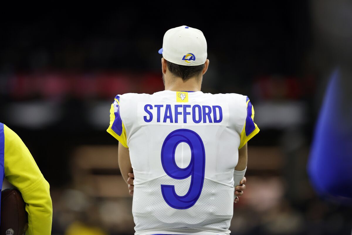 As seen from the back, Rams quarterback Matthew Stafford watches from the sideline.