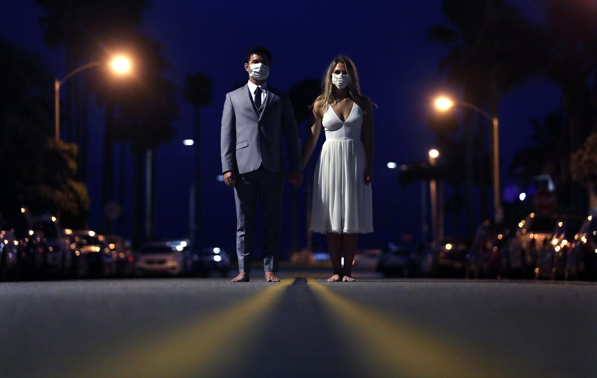 Jonathan Gryn and Debbie Rey model their wedding clothes barefoot in the street at night near their home in Huntington Beach.