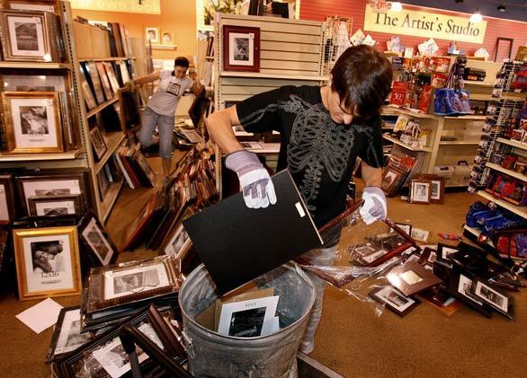 Aaron Brothers employees Justy Koch, left, and Ben York clean up several hundred picture frames knocked from shelves in Brea. Employees spent eight hours the night before stocking the shelves with 2,700 new frames in preparation for a visit from the company's president.