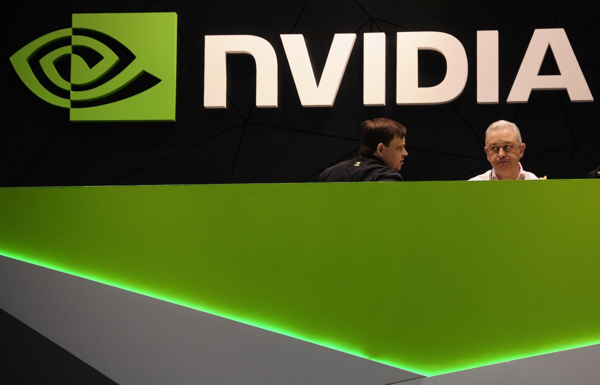 Two people talk in the Nvidia booth at a mobile phone trade show.