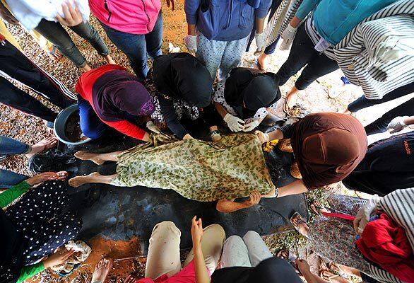 Volunteers carry the body of a dam collapse victim at a makeshift morgue outside Jakarta, Indonesia. The collapse sent a deadly wall of mud and water crashing into homes as people slept.