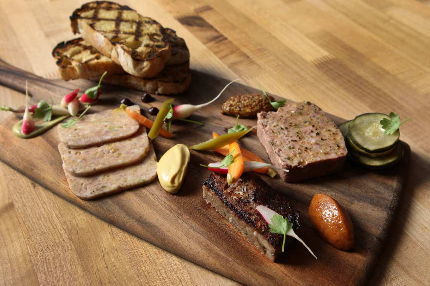 A board with house-made charcuterie, pickled vegetables and mustards.
