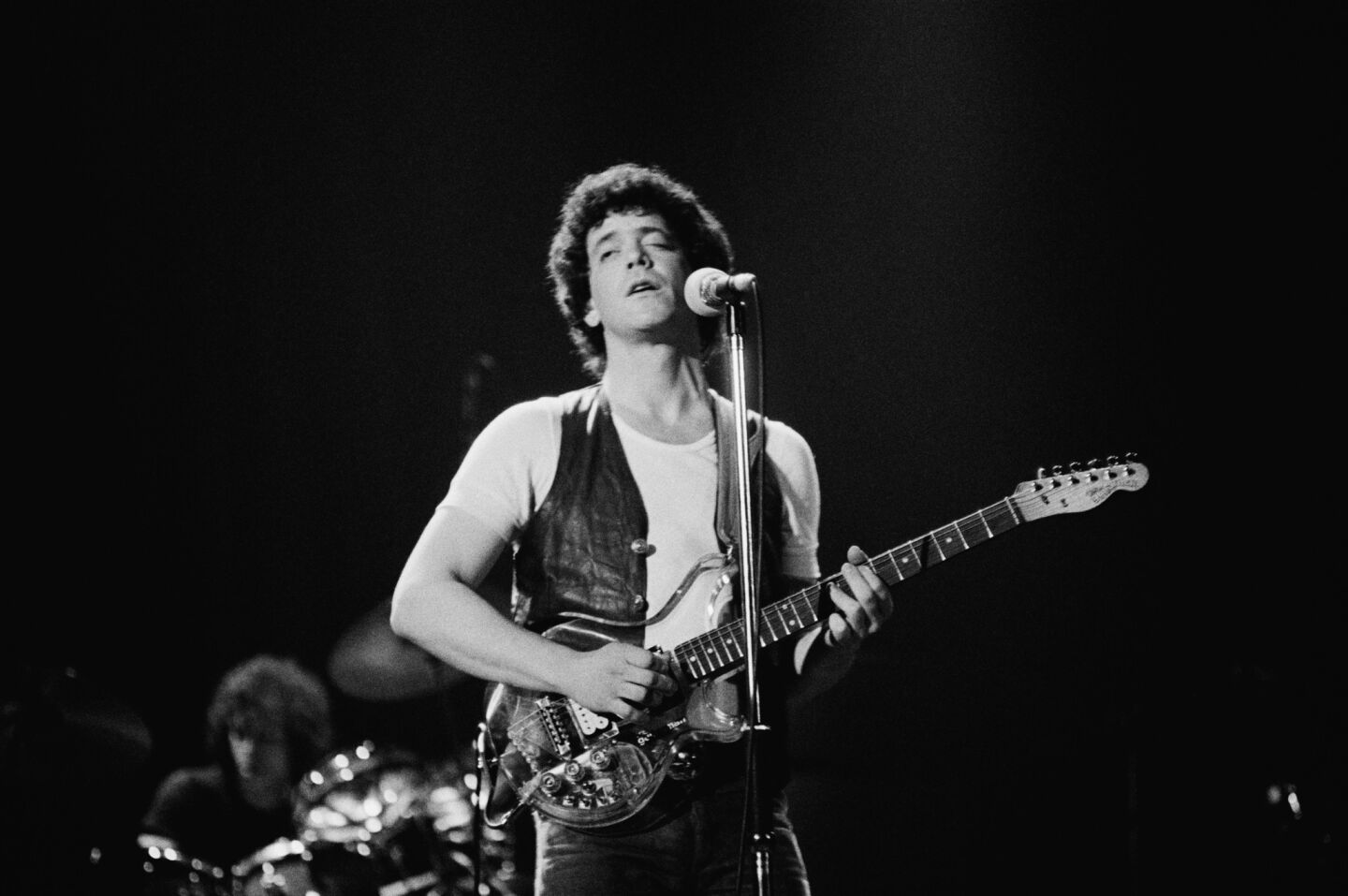 Playing a plexiglass guitar, Lou Reed performs at the Hammersmith Odeon in London in 1975.