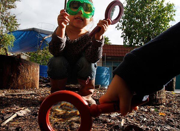 Echo Rodriguez, 3, watches as Rashid Macias, 4, uses a magnifying glass to look for earthworms in the loamy soil of the Brooklyn Early Education Center's outdoor classroom in East Los Angeles. Outdoor education is a way to connect children to nature and make learning fun. The classrooms must be certified, and the teachers are specially trained.