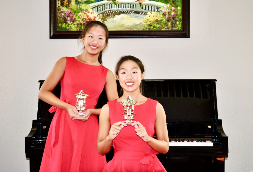 Olina and Olivia Xia holding their first place trophies from the recent Piano Duet/Ensemble Contest of Carmel Valley Tame.