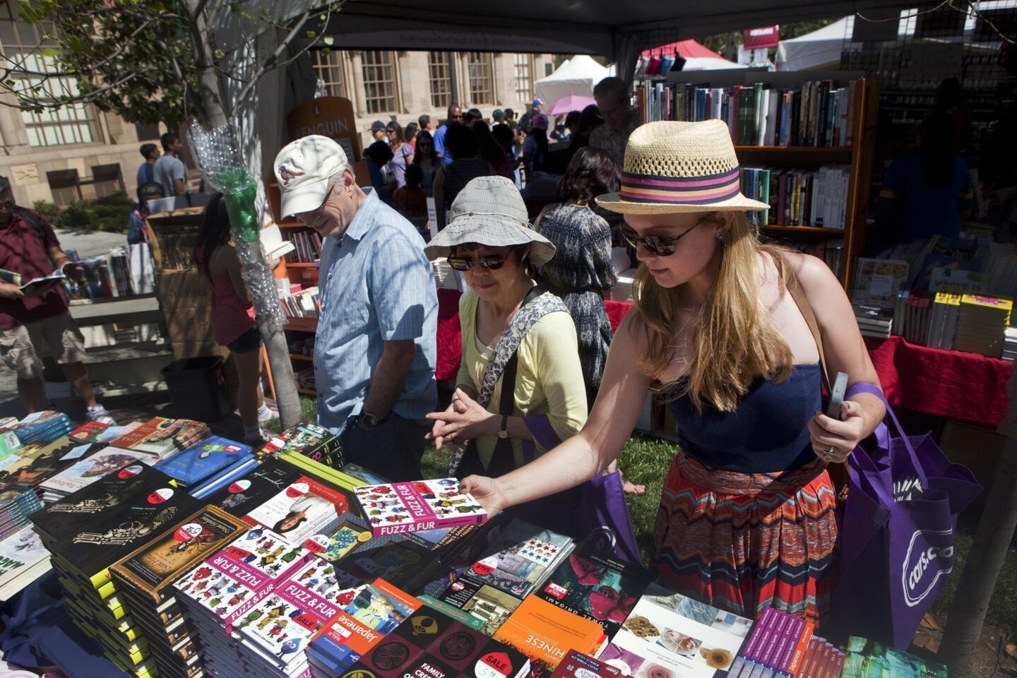 David and Diane Plaskow, left, look over piles of books along with USC freshman Storm Nylen during the first day of the 2013 Los Angeles Times Festival of Books on Saturday.