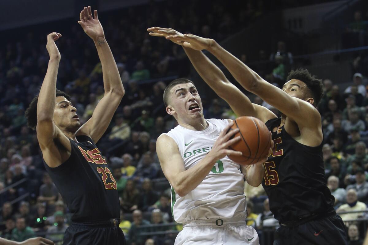 Oregon's Payton Pritchard, center, goes up for a shot between USC's Max Agbonkpolo, left, and Isaiah Mobley, right, during the first half on Thursday in Eugene, Ore.