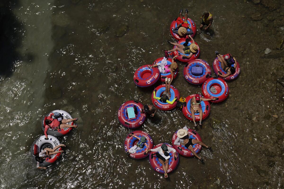 Bañistas en llantas inflables flotan en el frío río Comal, 