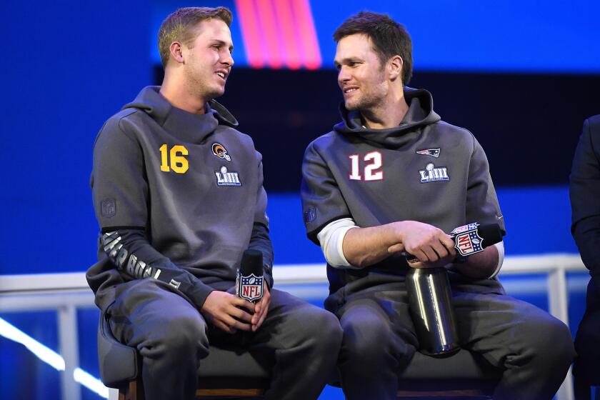 Rams quarterback Jared Goff, left, and Patriots quarterback Tom Brady talk on stage during media day.