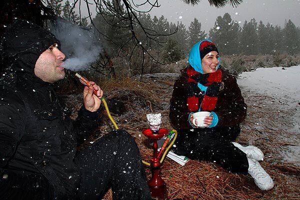 Arman Boghian, left, puffs on a hookah while Daean Ghania enjoys a cup of hot tea while picnicking along Mt. Pinos Road in Cuddy Valley. The road was closed to traffic because of heavy snow above the valley.
