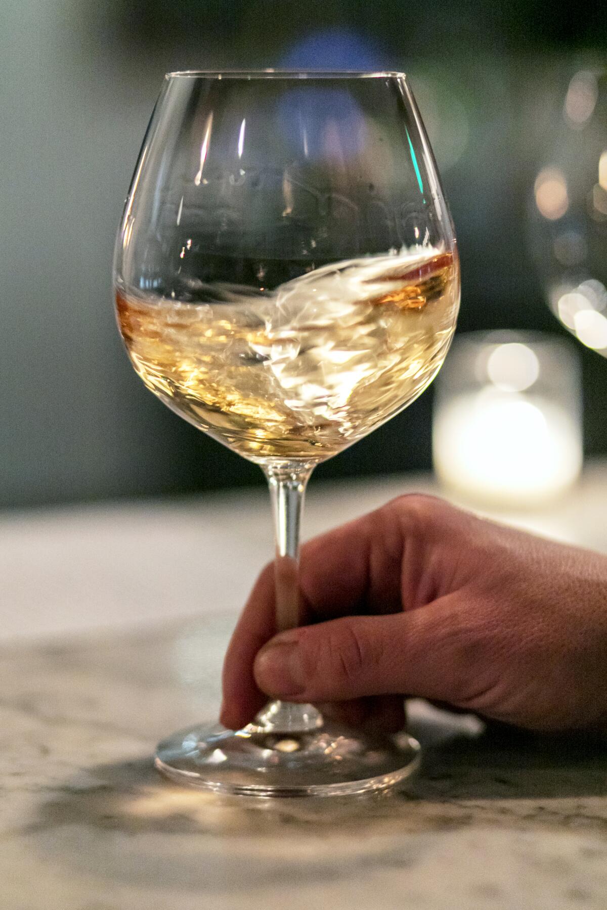 A person swirls wine in a wine glass 