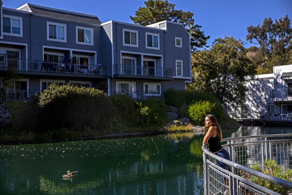 A woman looks out at a pond from behind a fence.