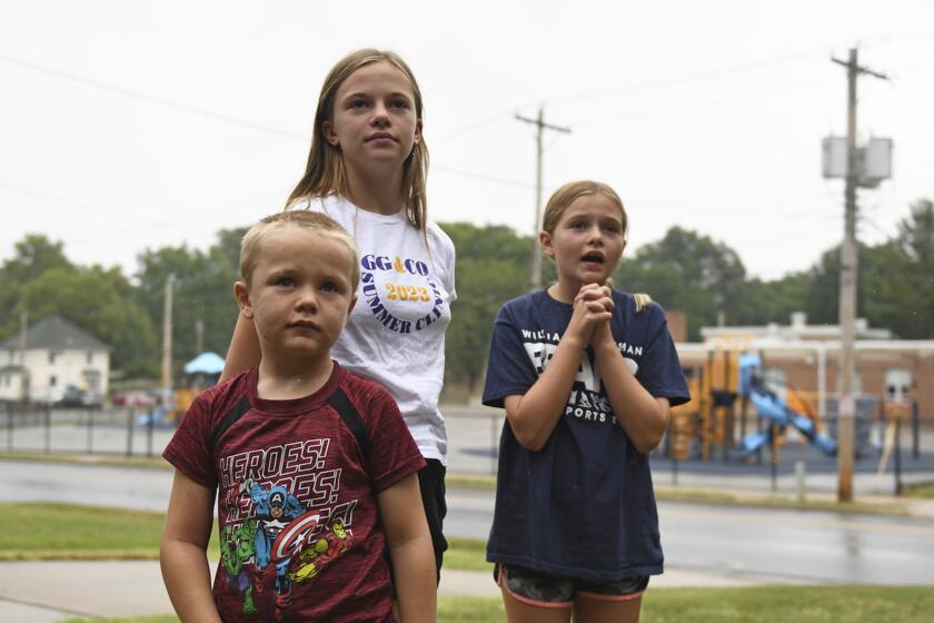 Hudson, 7, left, Callahan, 13, middle, and Keegan Pruente, 10, right, stand outside their school on their first Monday home during the new four-day school week on Monday, Sept. 11, 2023, in Independence, Mo. Hundreds of school systems around the country have adopted four-day weeks in recent years, mostly in rural and western parts of the U.S. Districts cite cost savings and advantages for teacher recruitment. Still, some experts question the effects on students who already missed out on significant learning during the pandemic. (AP Photo/Nick Ingram)