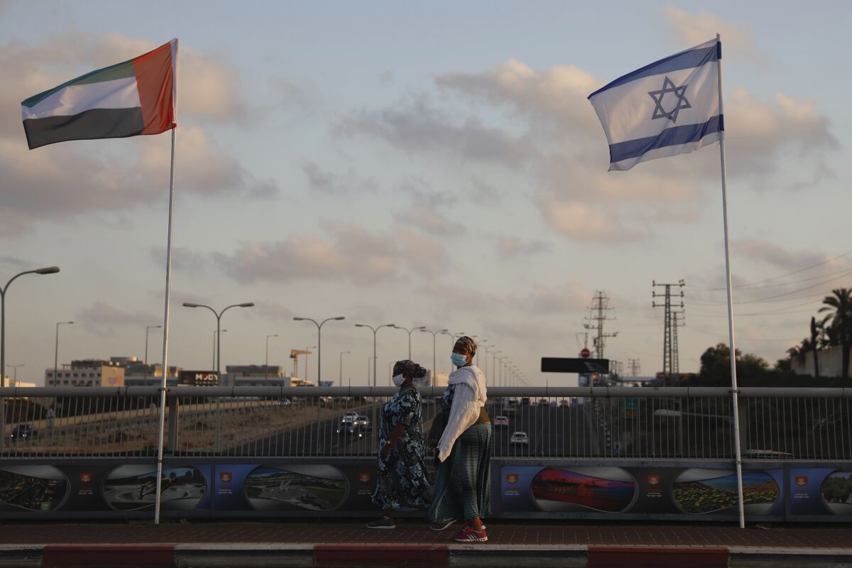 Women walk past United Arab Emirates and Israeli flags 