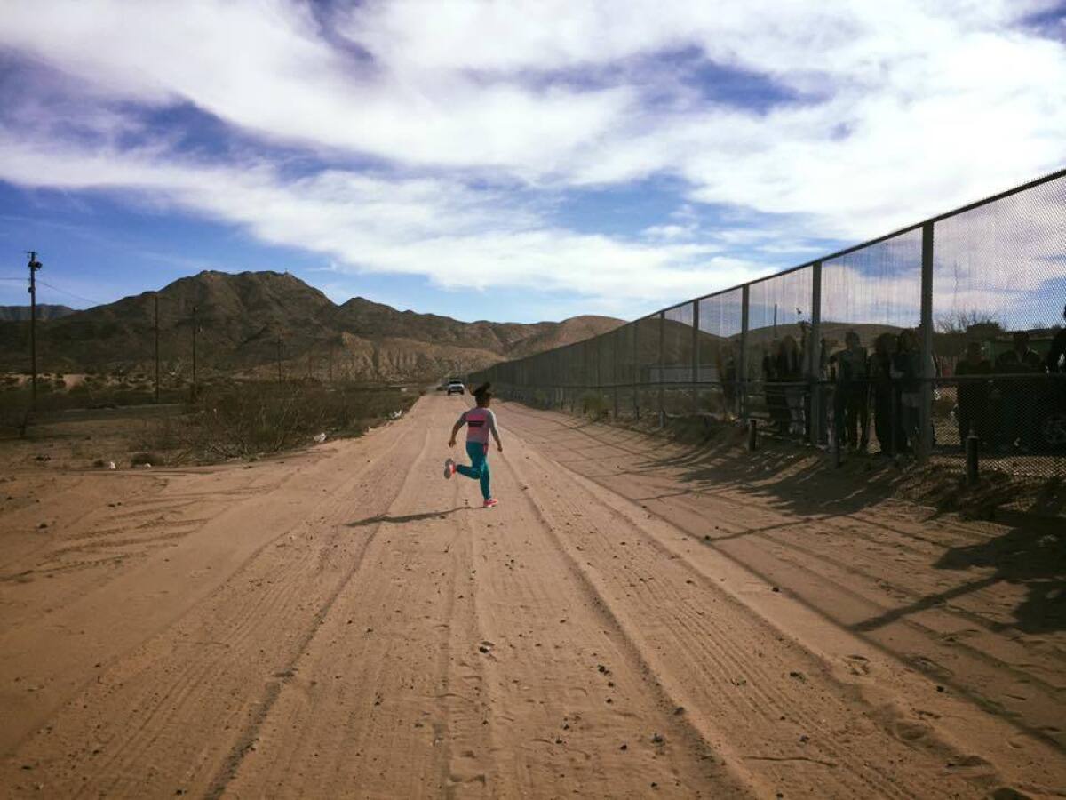 On the U.S. side, one of the youngest members of the family runs toward the fence and her family on the Mexican side.